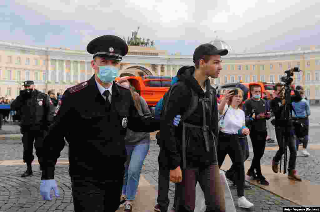 Полицейский задерживает митингующего во время акции протеста в Санкт-Петербурге