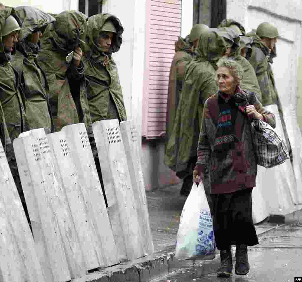 A woman walks past a line of riot policemen during a protest rally outside the Georgian parliament in Tbilisi on November 11.