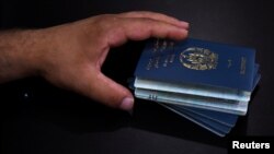 Afganistanac, korisnik američke specijalne imigrantske vize (SIV), drži pasoše svoje porodice dok potpisuju ugovor o najmu novog stana nakon evakuacije iz Afganistana u Houstonu, Teksas, avgust 2021.