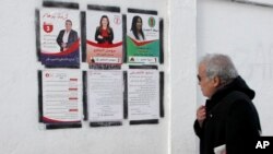 یک مرد تونسی در پایتخت تونس به پوسترهای انتخاباتی نگاه می‌کند؛ روز شنبه دوم دی 