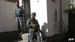 Afghan policemen stand guard near the body of a suicide bomber inside a United Nations compound in Herat.