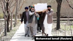 Afghan Sikhs men carry the coffin of one of the victims of a deadly extremist attack on a Sikh religious complex in Kabul that killed dozens of people in late March.