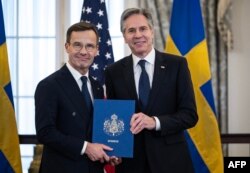 Premierul suedez Ulf Kristersson îi înmânează secretarului de stat american Antony Blinken documentele de ratificare pentru aderarea Suediei la NATO. Washington D.C., 7 martie.