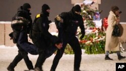 Ofițeri de poliție rețin un bărbat după ce acesta a depus flori la Memorialul victimelor represiunilor politice din Sankt Petersburg, pe 16 februarie.