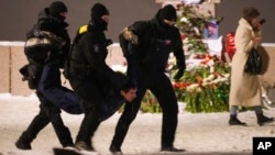 Police officers detain a man laying flowers to Aleksei Navalny at the Memorial to Victims of Political Repression in St. Petersburg on February 16.