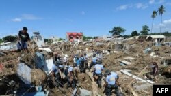 Policemen dig among debris and destroyed houses during rescue operations following floods in Iligan City in the Philippines.