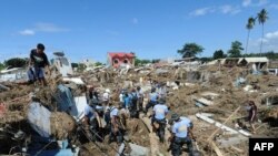 Policemen dig among debris and destroyed houses during rescue operations following floods in Iligan City in the Philippines. 