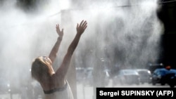 Дівчина охолоджується водяними бризками від розпилювача прохолодної води, встановленого в центрі Києва, 12 серпня 2019 року