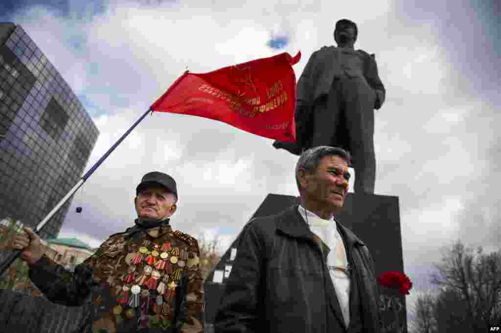 People hold flags and flowers as they arrive to pay tribute to Lenin by a statue in Donetsk, eastern Ukraine, on April 22, the 145th anniversary of his birth. (AFP/Behrouz Mehri) 