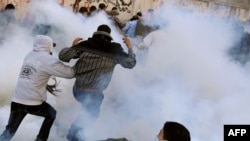 A protester prepares to hurl a tear-gas canister back at security forces as others run for cover on the third day of clashes on Tahrir Square in Cairo on November 21.