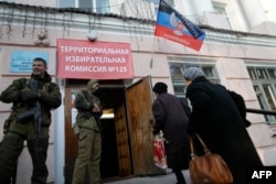 Two voters walk past pro-Russian rebels at a polling station in Donetsk.