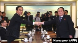 Оңтүстік Кореяның бірігу министрі Чо Мён Гён (сол жақта) мен Солтүстік Кореяның бейбіт бірігу комитетінің төрағасы Ри Сон Гвон қол алысып тұр. 9 қаңтар 2018 жыл. 