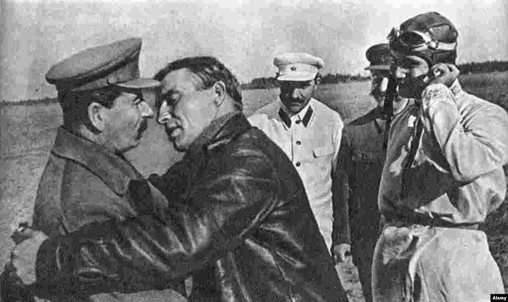 Soviet dictator Josef Stalin looks unsure as pilot Valery Chkalov (right) leans in for a kiss in 1936.&nbsp;