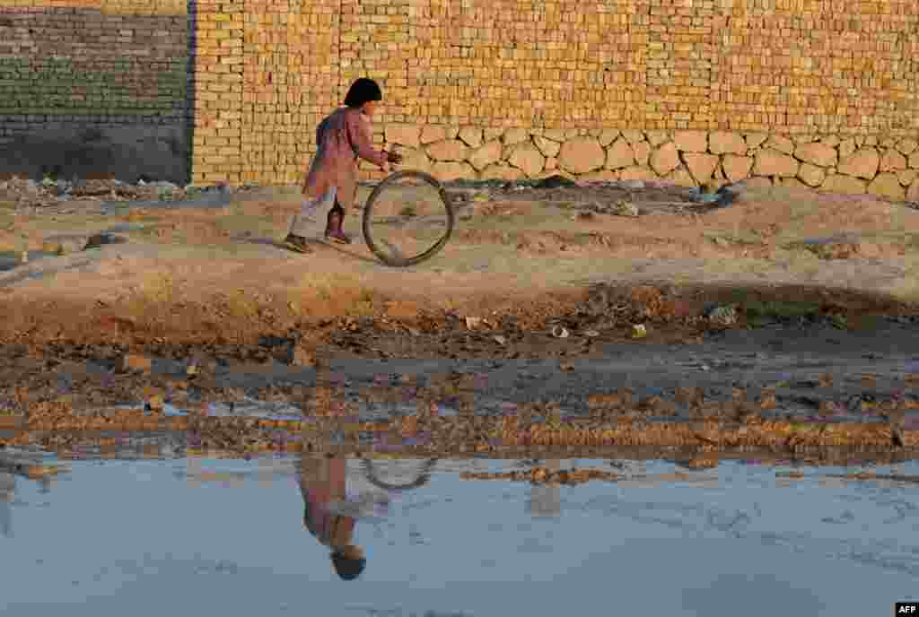 An Afghan child plays with a tire in the Afghan city of Mazar-e Sharif on November 25. (AFP/Farshad Usyan)