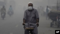 Biciklista, sa maskom, na putu za posao dok smog obavija oblasti Lahora, Pakistan, sreda, 6. novembra 2024. 