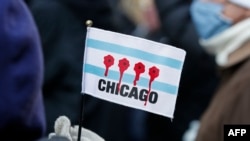Една жена држи мало знаме на кое се прикажани дупки од куршуми со крв за време на маршот против оружјето во Чикаго, Илиноис, на 31 декември 2020 година.