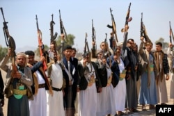 Armed Yemenis brandish their weapons as they rally in solidarity with Lebanon and Iran on the outskirts of the Houthi-controlled capital, Sanaa, on July 2.