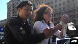 There are fears that Russian authorities might use a broader definition of treason to target dissenters. Here, a police officer detains a protester wearing white ribbons, a symbol of the Russian opposition, just outside the State Duma in Moscow in June.