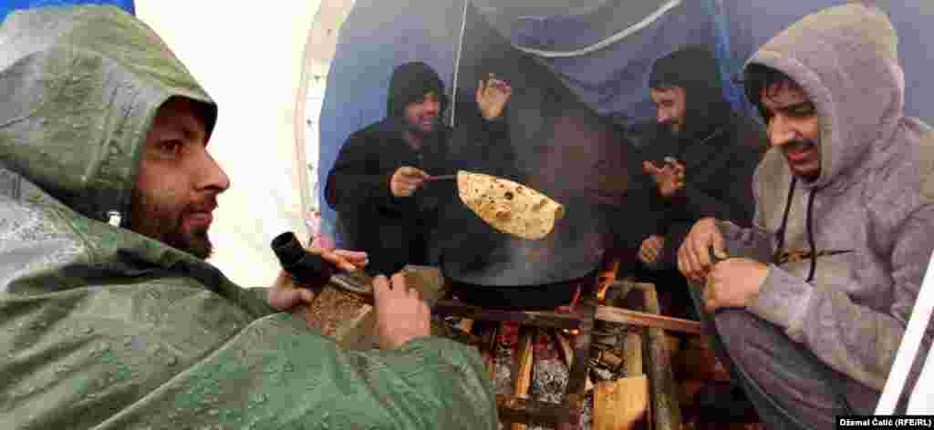 Refugees and migrants in Bosnia sit around a fire in temporary housing at the burned-out Lipa camp in cold weather on January 3. (RFE/RL/Dzemal Catic)