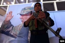 Афганский солдат стоит на фоне портрета вице-президента Афганистана Абдула Рашида Дустума. Герат, 30 августа 2015 года.