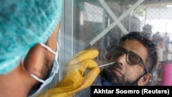 Пакистанда медкызматкер коронавируска тест алып жатат. Карачи шаары. 6-июль, 2020-жыл.
