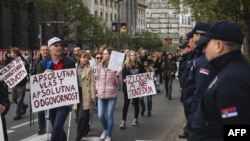 Protestatarii poartă pancarte pe care „Câte vieți veți mai distruge?”, „Putere absolută, responsabilitate absolută” și „E o crimă, nu o tragedie”. Ei trec pe lângă polițiștii sârbi în fața clădirii Guvernului în timpul unei demonstrații organizate de studenții belgrădeni.