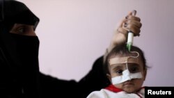 Зане бо ёрии васоили тиббӣ духтари дучори гуруснагиашро ғизо медиҳад. Беморхонаи Санъо, Яман, соли 2020
