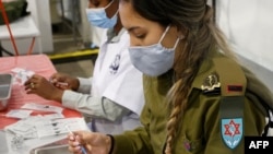 Израильдік әскери дәрігер коронавирусқа қарсы Pfizer-BioNTech вакцинасын салуға дайындалып отыр. Ришон-ле-Цион, Израиль, 28 желтоқсан 2020 жыл.