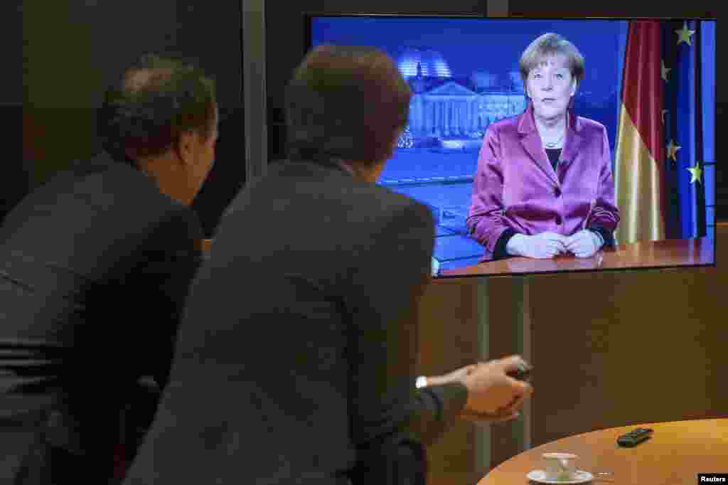 مردم در حال تماشای سخنرانی آنگلا مرکل به مناسبت سال نوی میلادی در آلمان