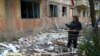 A woman stands near her apartment building, which was damaged in a night attack in the town of Selydove, in Ukraine's Donetsk region, on April 14.