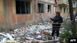 A woman stands near her apartment building, which was damaged in a night attack in the town of Selydove, in Ukraine's Donetsk region, on April 14.