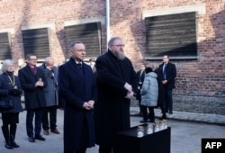 Președintele polonez Andrzej Duda (stânga) și Piotr Cywiński (dreapta), directorul Muzeului Auschwitz-Birkenau, participă la o ceremonie de depunere de coroane la așa-numitul Zid al Morții de lângă fostul bloc 11 al fostului lagăr principal Auschwitz I din Oswiecim, Polonia.