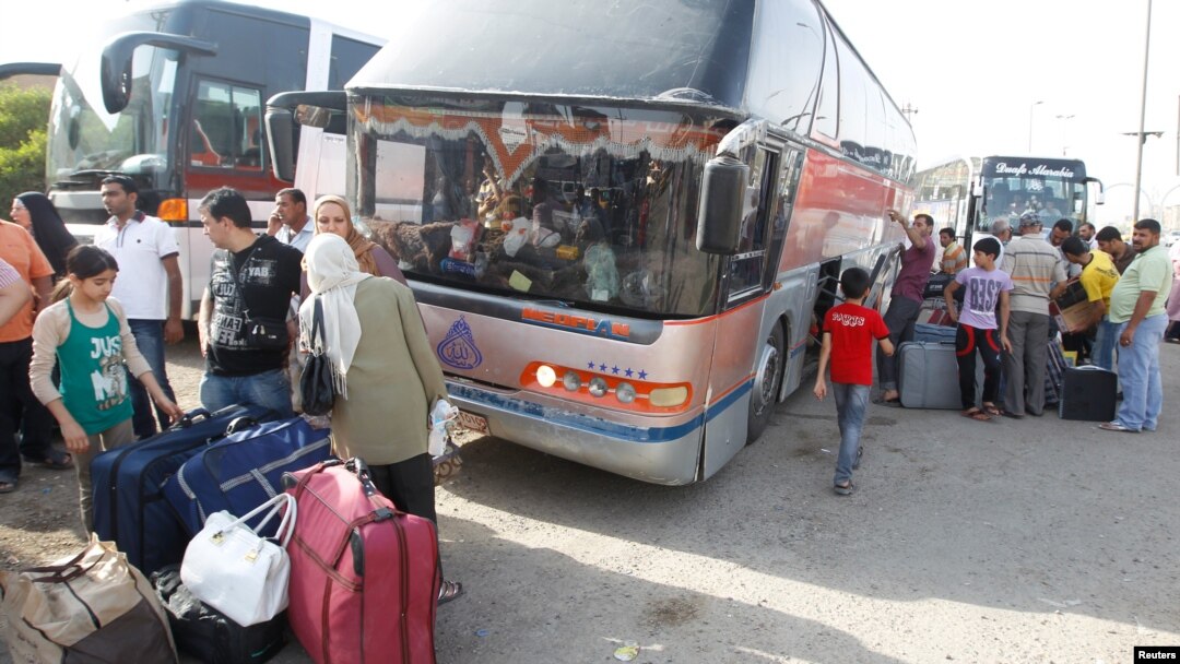 People unload their belongings in Baghdad from a bus that had traveled from Syria on July 20.