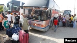 People unload their belongings in Baghdad from a bus that had traveled from Syria on July 20.