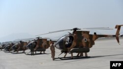 An Afghan pilot stands next to a line of U.S.-made MD-530 helicopters in Kabul.