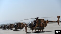 An Afghan pilot stands next to a line of U.S.-made MD-530 helicopters in Kabul.