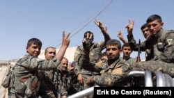 Fighters of the Syrian Democratic Forces gesture a "V" sign to the media as they ride a truck on the way to the frontline in Raqqa, October 8, 2017