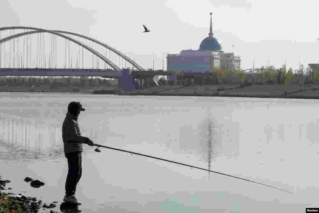 A man fishes on an embankment of the Ishim River in Astana, as Akorda, the official residence of the Kazakh president, is seen in the background. (Reuters/Shamil Zhumatov)