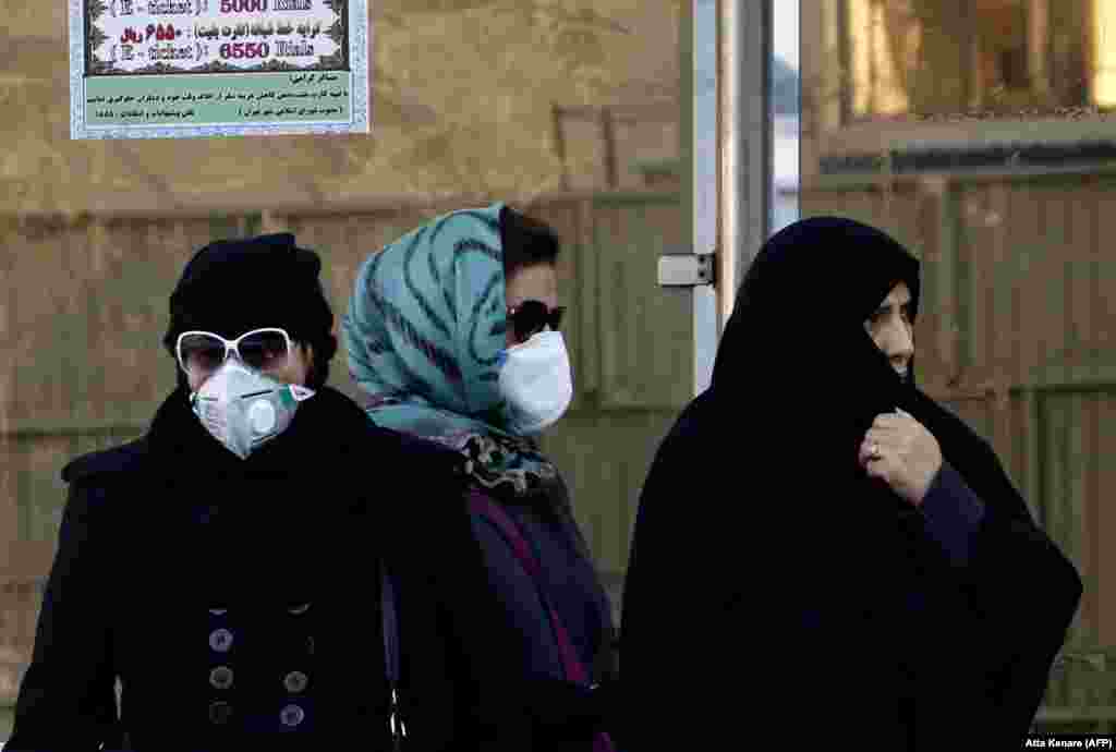 Iranian women wearing face masks wait at a bus stop as winter&#39;s heavy pollution hits new highs in the capital Tehran. (AFP/Atta Kenare)