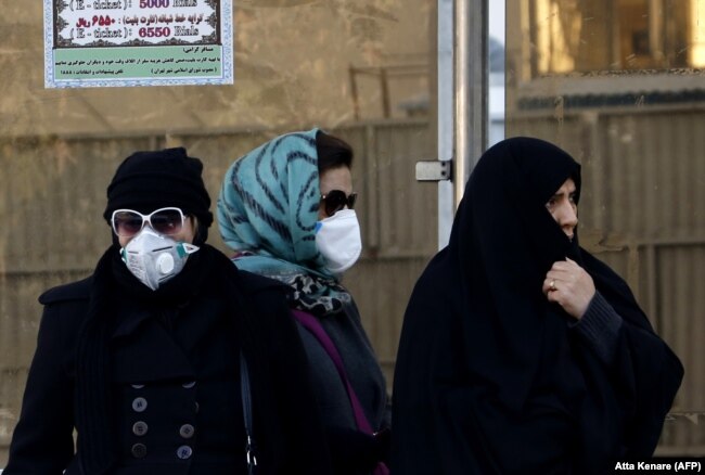 Iranian women wearing face masks wait at a bus stop in Tehran, which has long been plagued by a pollution problem. (file photo)