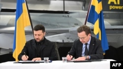 Prim-ministrul suedez Ulf Kristersson (R) și președintele ucrainean Volodimir Zelenski semnează o scrisoare de intenție pentru dezvoltarea capabilităților aeriene la Linköping, Suedia, pe 22 octombrie 2025.