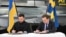 Prim-ministrul suedez Ulf Kristersson (R) și președintele ucrainean Volodimir Zelenski semnează o scrisoare de intenție pentru dezvoltarea capabilităților aeriene la Linköping, Suedia, pe 22 octombrie 2025.