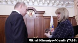 Ella Pamfilova, the chairwoman of the Central Election Commission, hands Russian President Vladimir Putin his identity card after his election victory, during a meeting at the Kremlin on April 3.