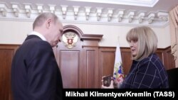 Ella Pamfilova, the chairwoman of the Central Election Commission, hands Russian President Vladimir Putin his identity card after his election victory, during their meeting at the Kremlin in Moscow, April 3, 2018