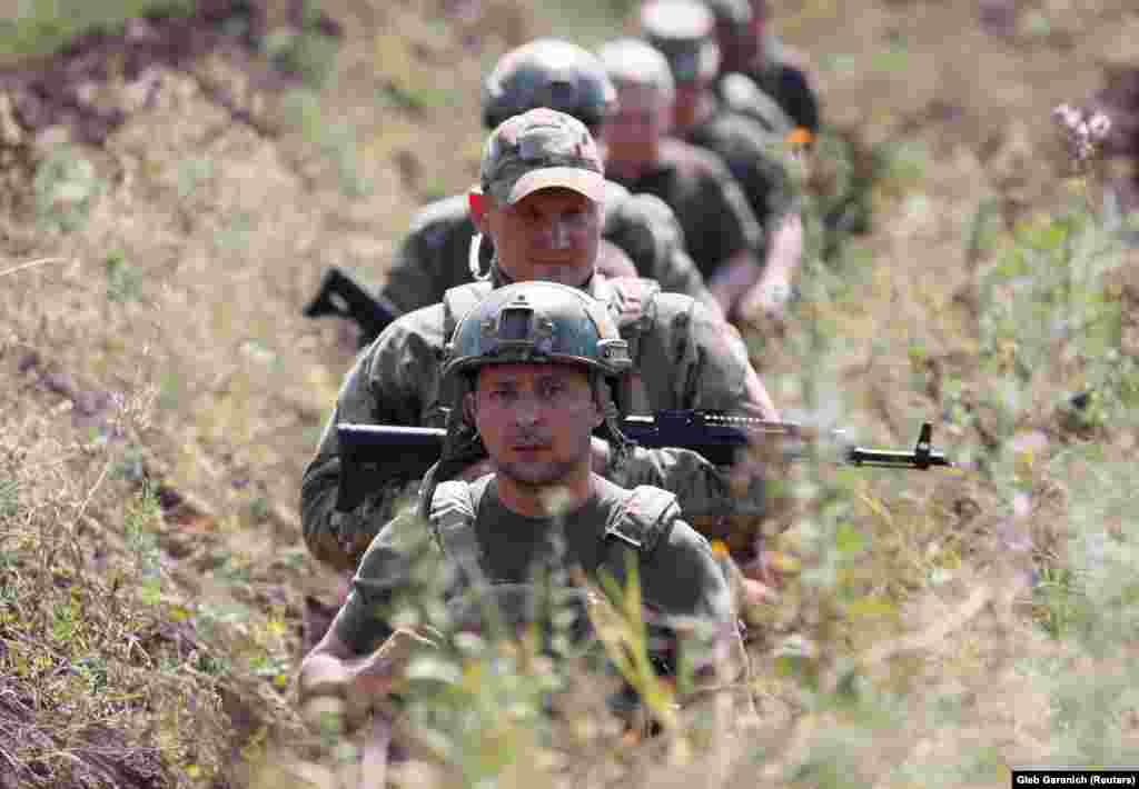 Ukrainian President Volodymyr Zelenskiy and servicemen walk in a trench near the frontline with Russian-backed separatists in Ukraine&#39;s Donetsk region. (Reuters/Gleb Garanich)