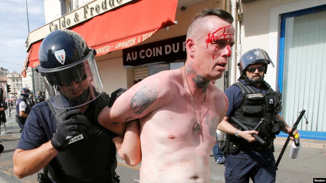 An injured man is led away by French police in Marseille following clashes between Russia and England supporters after a 1-1 draw in Marseille on June 11.