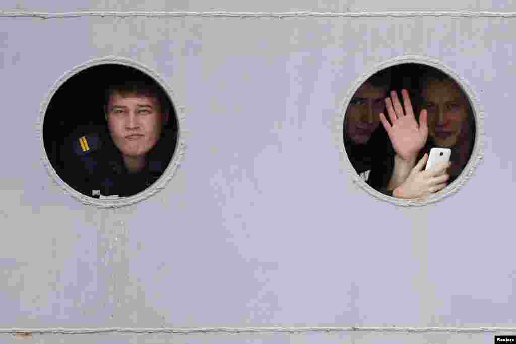 Russian sailors look through the portholes of the Russian Navy frigate "Smolny" as they leave a shipyard in western France. The Russian sailors have been training for months on a French-built Mistral helicopter carrier. It is still unclear whether Paris will finally deliver the ship to Moscow. (Reuters/Stephane Mahe)