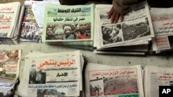 An Egyptian newspapers vender guards his papers fronted by pictures of the current situation in Egypt, Saturday, Feb. 5, 2011. President Barack Obama said Egypt's Hosni Mubarak should do the statesmanlike thing and make a quick handoff to a more represent