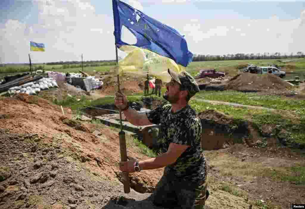 5 червня 2015 року. Український військовослужбовець тримає понівечений кулями прапор України на позиції біля міста Мар&#39;їнка. 3 червня поблизу Мар&rsquo;їнки, що біля Донецька, відбулося наймасштабніше після підписання Мінських угод протистояння між українськими військами та бойовиками. В ОБСЄ підтвердили, що наступ, та обстріли з важких озброєнь, заборонених Мінськими мирними домовленостями, почали бойовики. За даними української сторони, того дня під Мар&rsquo;їнкою загинули 4 військових, 38 були поранені. Сепаратисти подали такі дані своїх втрат: 14 загиблих, 86 поранених, із них тяжкопоранених &ndash; 18