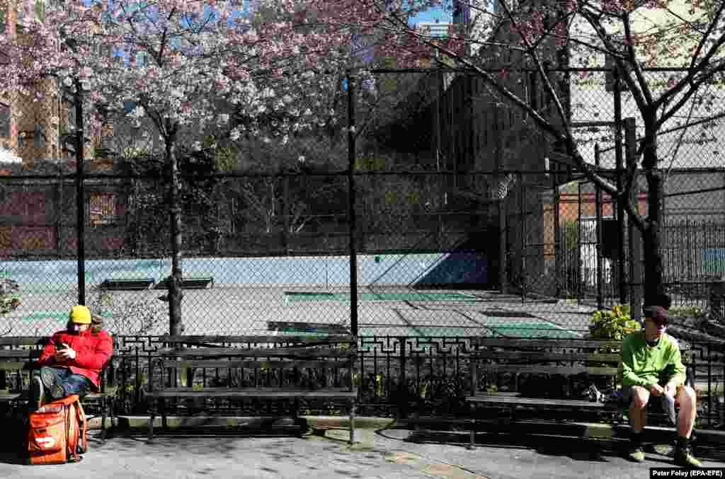 People practice social distancing while sitting in Hell&#39;s Kitchen Park in New York City on March 24.